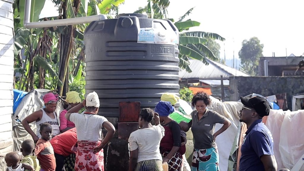 African women and children gather around a large water cistern