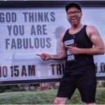 The Rev. Phil Hooper stands in front of a church sign reading "God thinks you are fabulous."