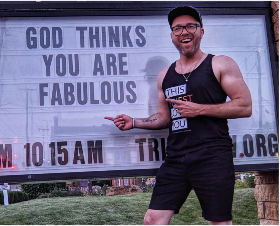 The Rev. Phil Hooper stands in front of a church sign reading "God thinks you are fabulous."