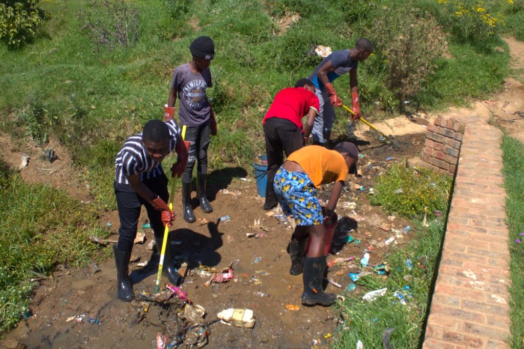 South African youths cleaning litter from the ground.